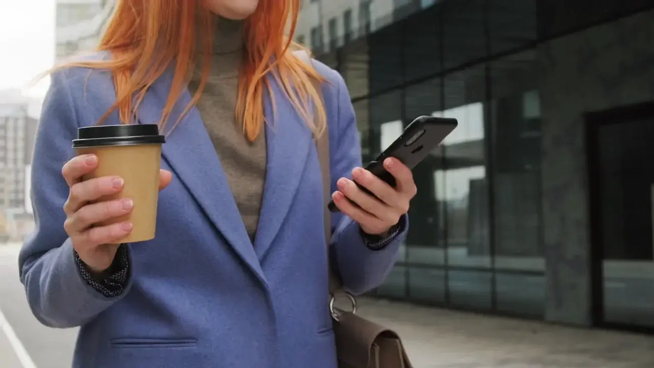 Poster image for stock video of someone walking outside while scrolling through her Smartphone